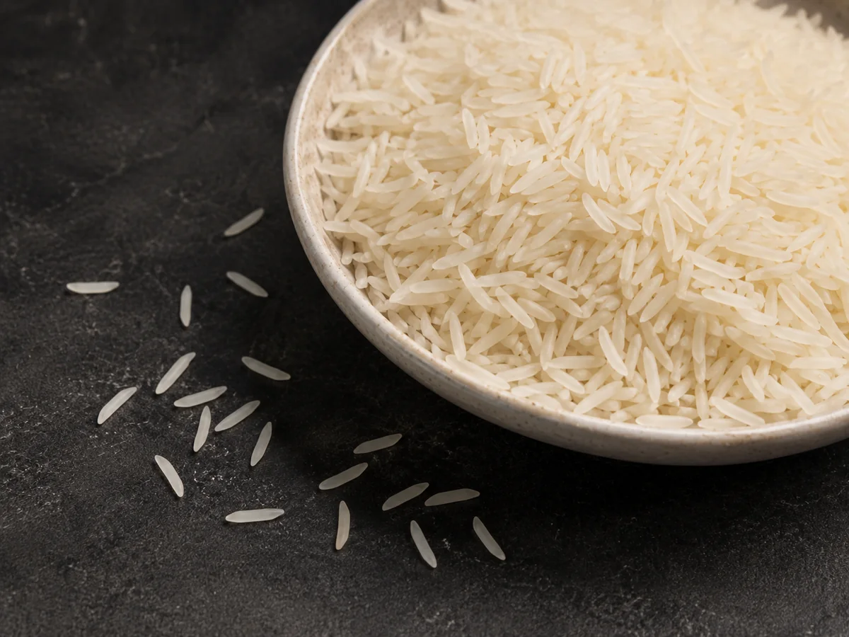 Premium Pakistani Basmati rice in a white bowl on a dark stone background